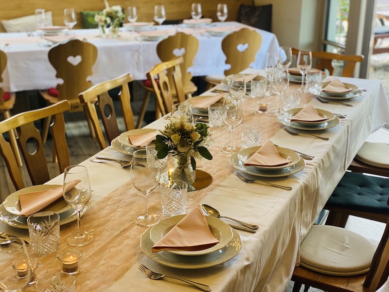 schön gedeckter Tisch mit Blumen und Weingläsern und Tellern im Wintergarten